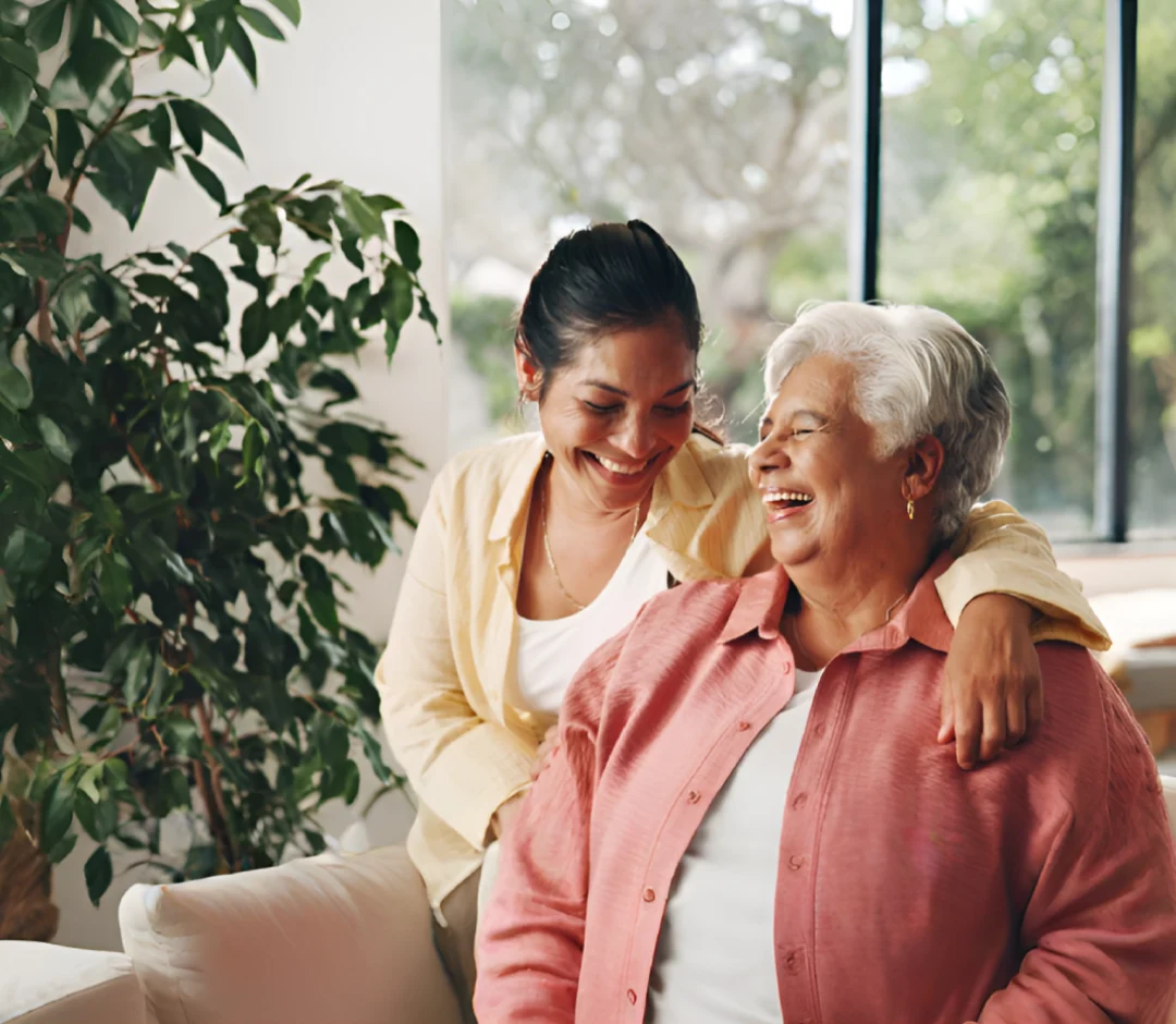 Alegria caregiver and an elderly client laughing together in her living room
