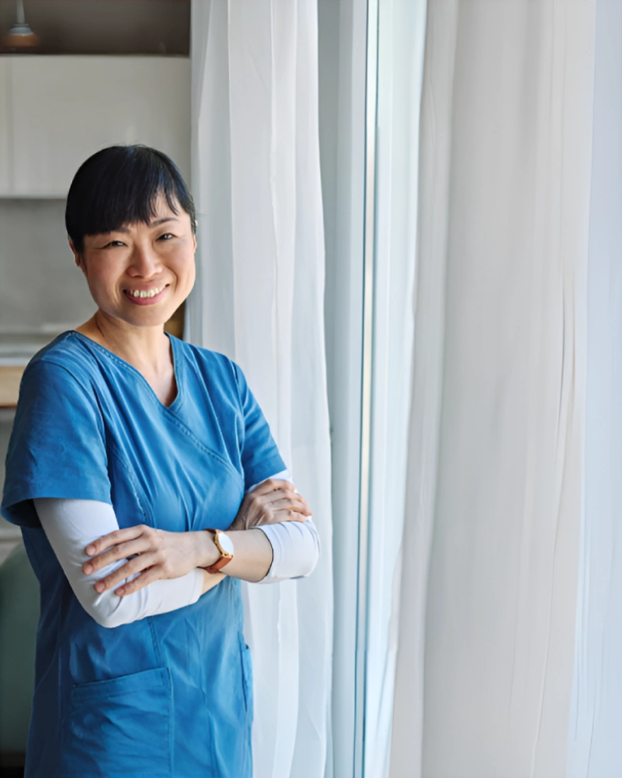 Smiling Alegria caregiver standing by a window in a client's home